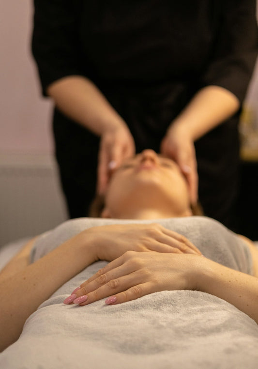 Een vrouw die een ontspannende gezichtsmassage krijgt in een spa‑omgeving.